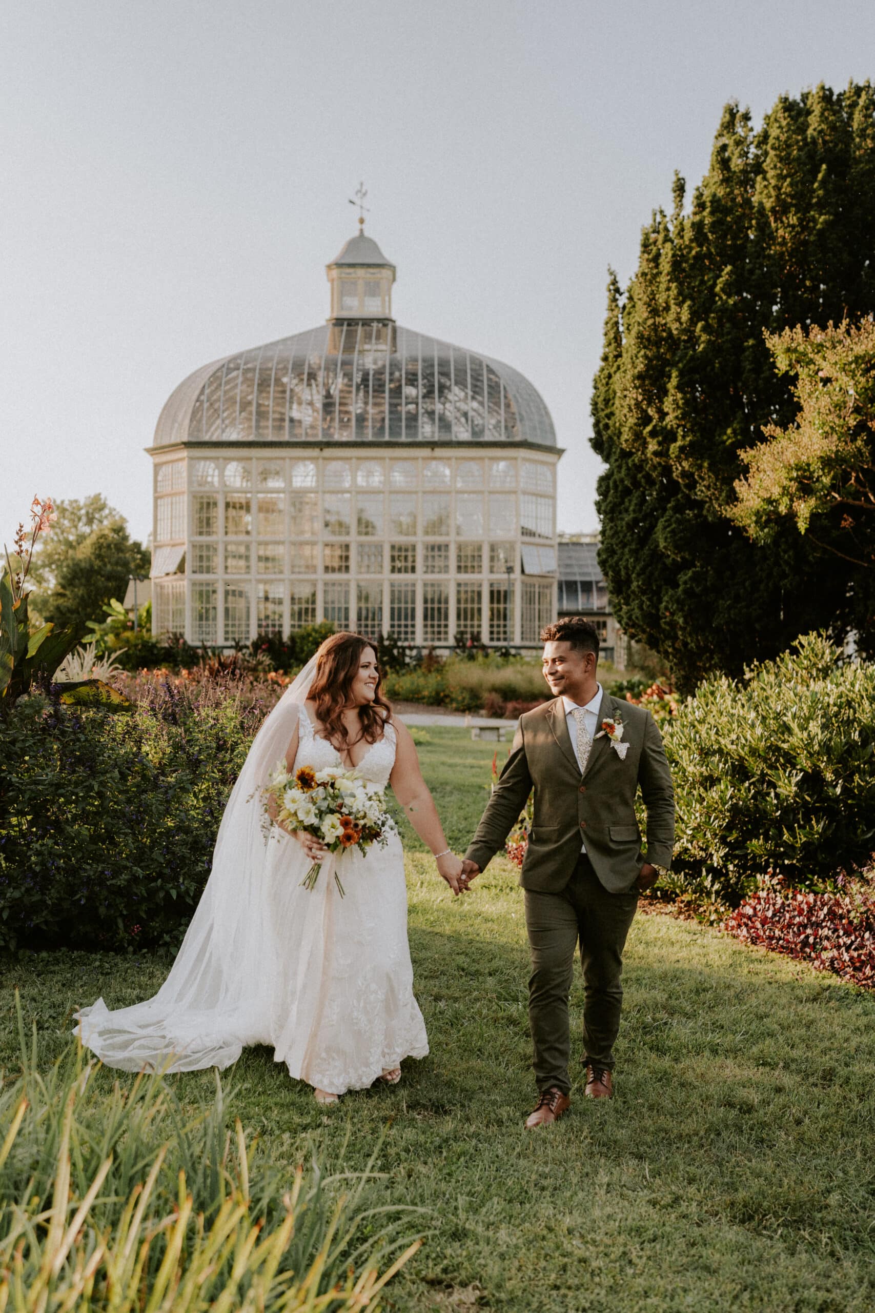 bride and groom holding hands outside of beautiful conservatory building