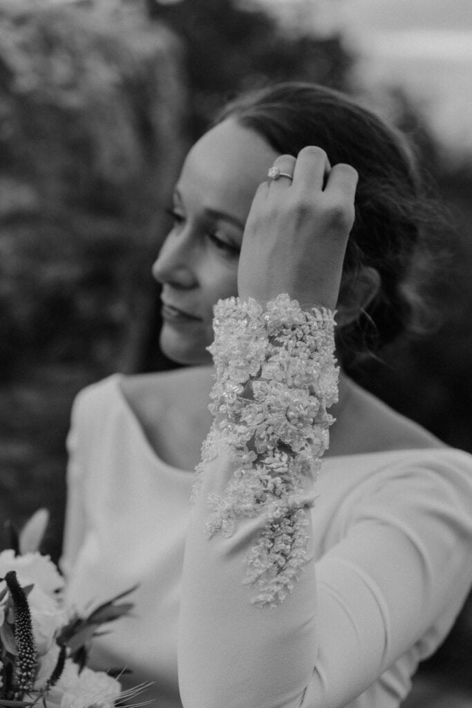 Black and white photo of bride with dress details and ring