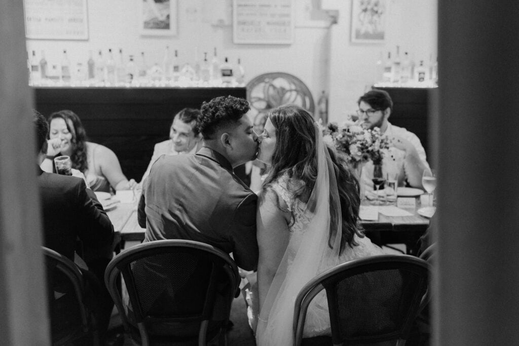 bride and groom kissing at dinner table