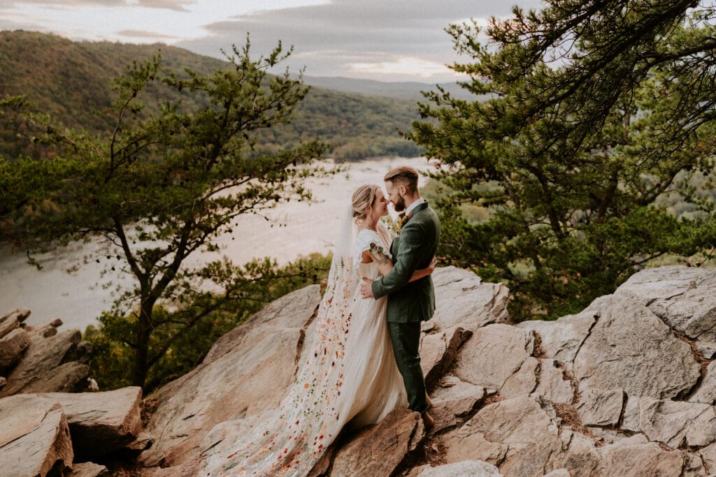 bride and groom embracing on edge of mountain 
