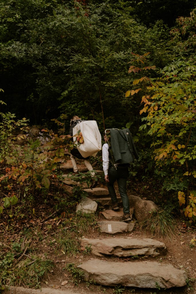 couple starting hike with wedding outfits on backpacks