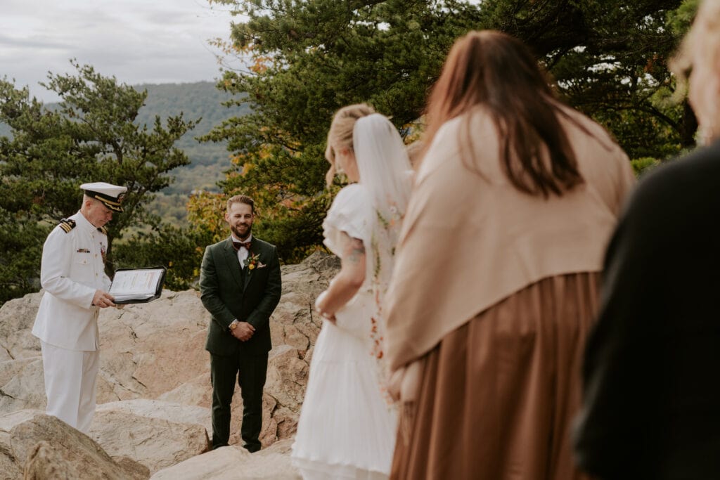 bride walking toward groom at ceremony on mountain