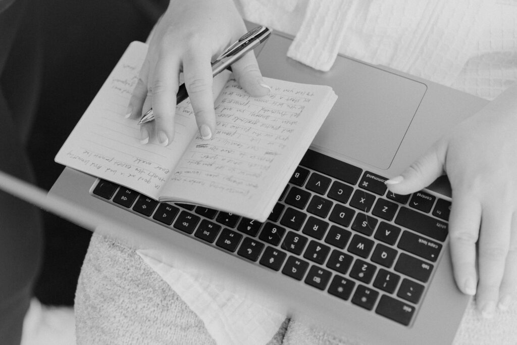 black and white photo of bride writing vows on laptop