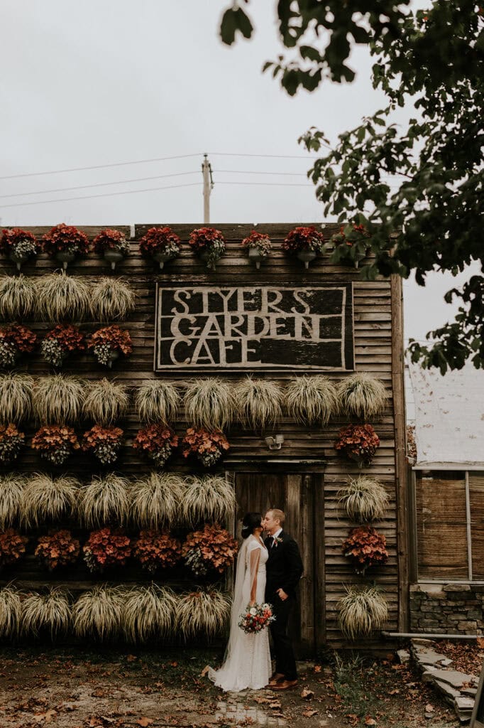 bride and groom kissing in front of styer’s garden cafe at terrain in pennsylvania