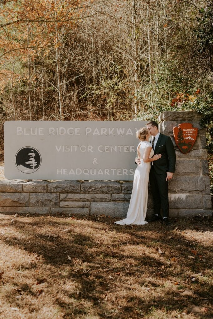 Bride and groom kissing in front of the Blue Ridge Parkway Visitor Center and Headquarters sign