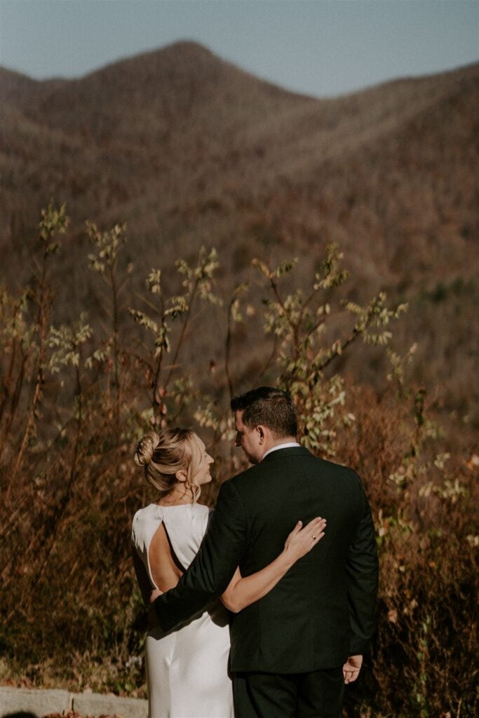 Bride and groom standing with arm around each other with mountains in the distance