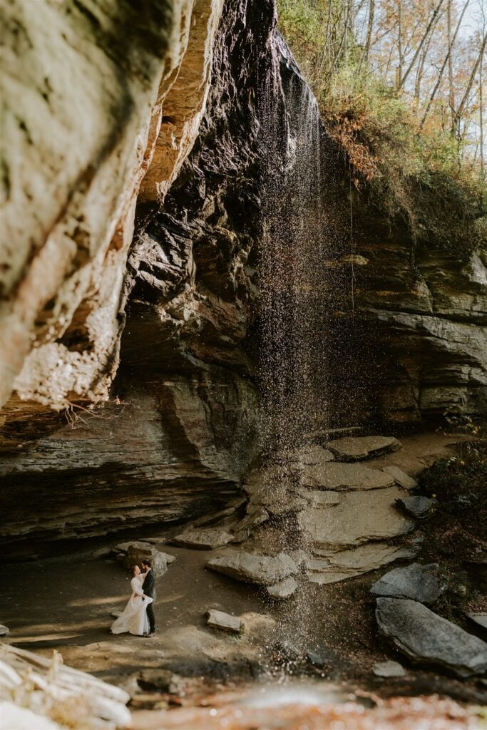 Bride and groom dancing under a waterfall near asheville north carolina