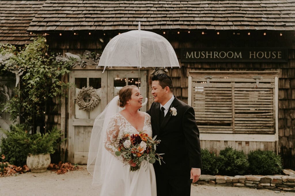 Bride and groom standing under umbrella in front of Mushroom House at Terrain wedding venue