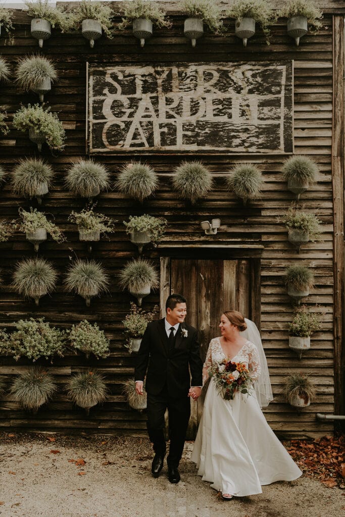 Bride and groom holding hands in front of Styer’s Garden Cafe building and sign