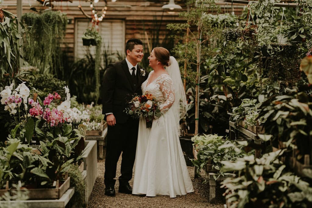 bride and groom standing in the greenhouse at terrain gardens wedding venue
