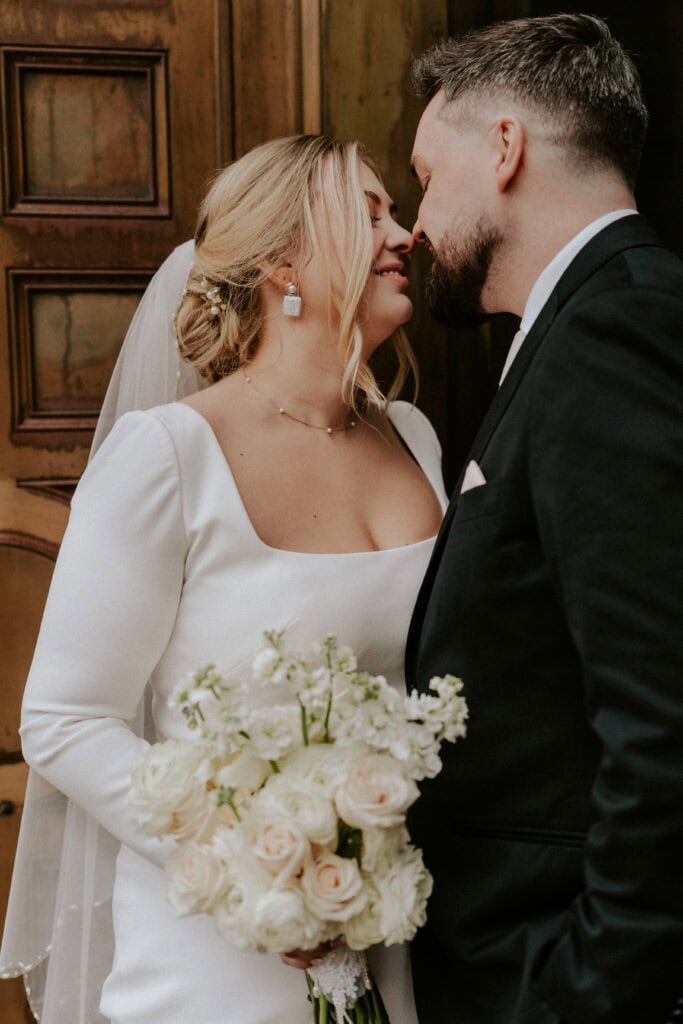 bride and groom almost kissing by a wooden door