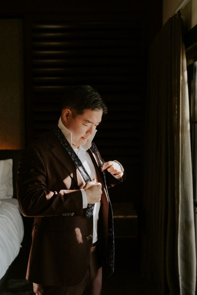 groom getting ready in front of a window