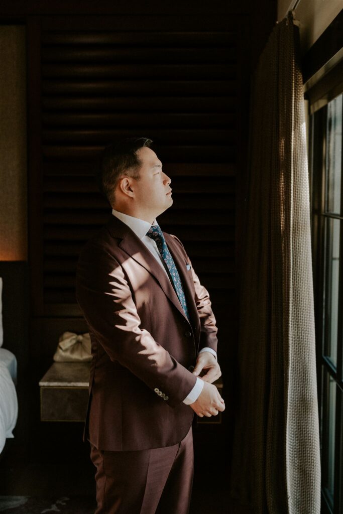 groom getting ready in front of a window