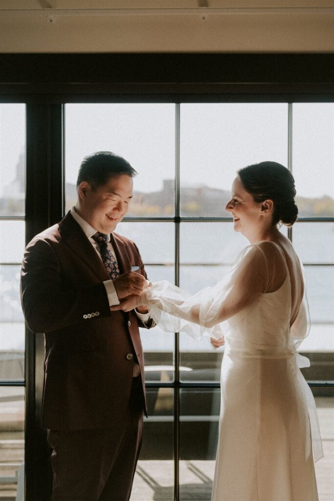 groom helping bride with final touches to her wedding look
