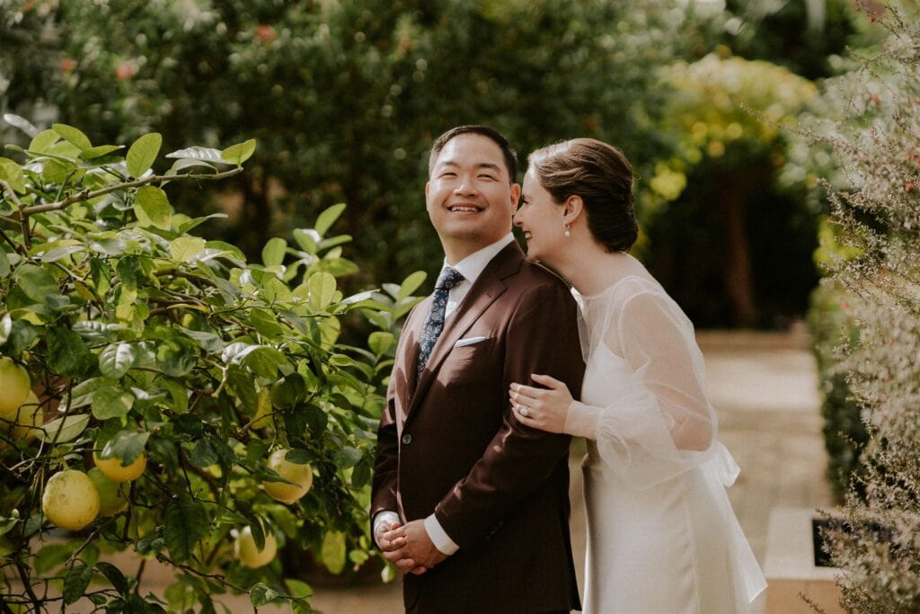 bride and groom walking around the rawlings conservatory during their baltimore elopement day surrounded by lush greenery and flowers