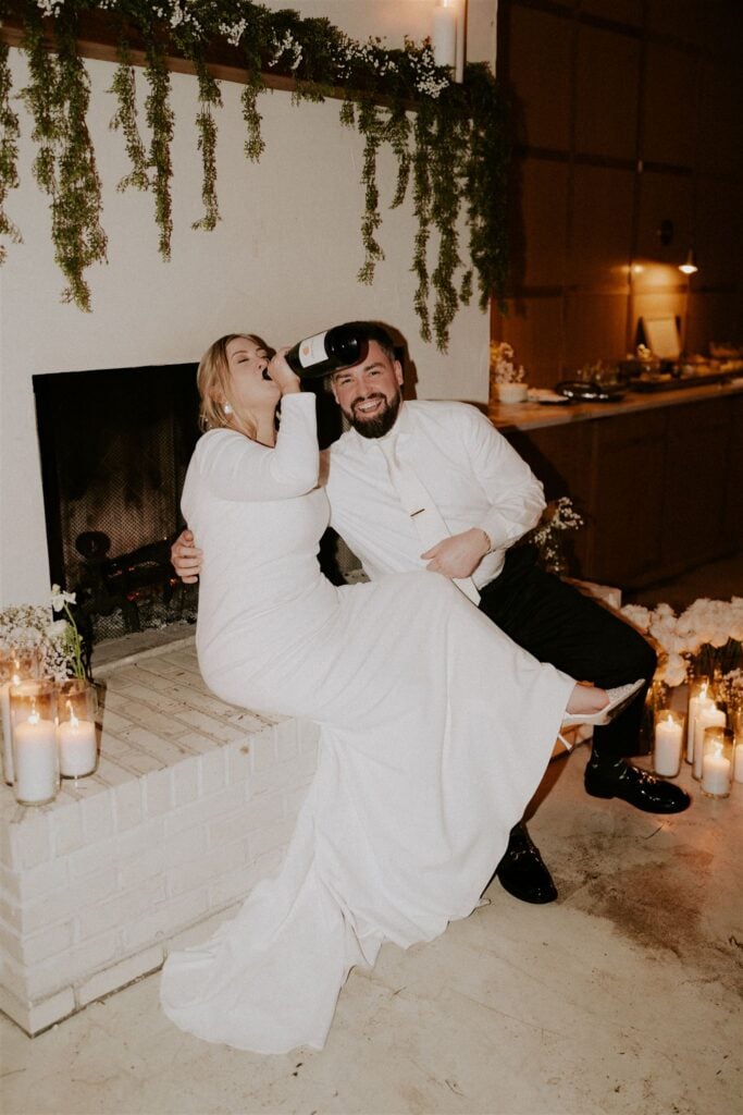 bride and groom sharing a bottle of champagne
