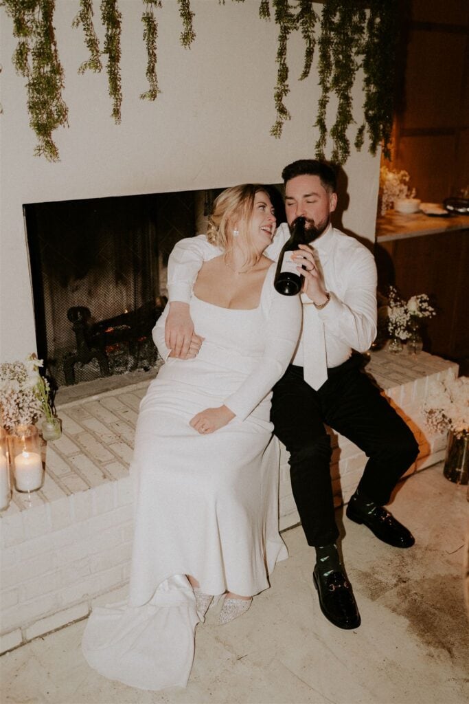 bride and groom sharing a bottle of champagne