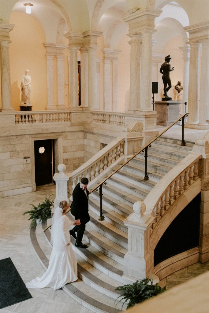 bride and groom walking the stairs at the walters art museum