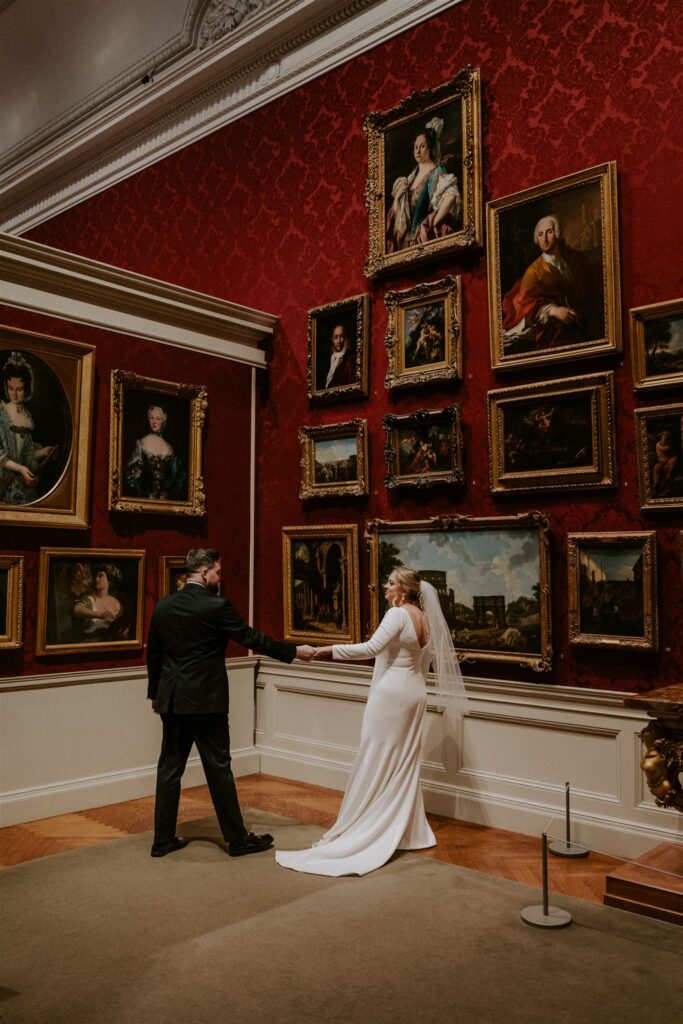 bride and groom posing in front of art at the walters art museum