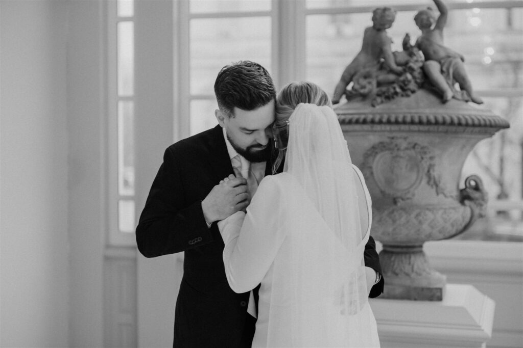bride and groom hugging next to a sculpture at the walters art museum