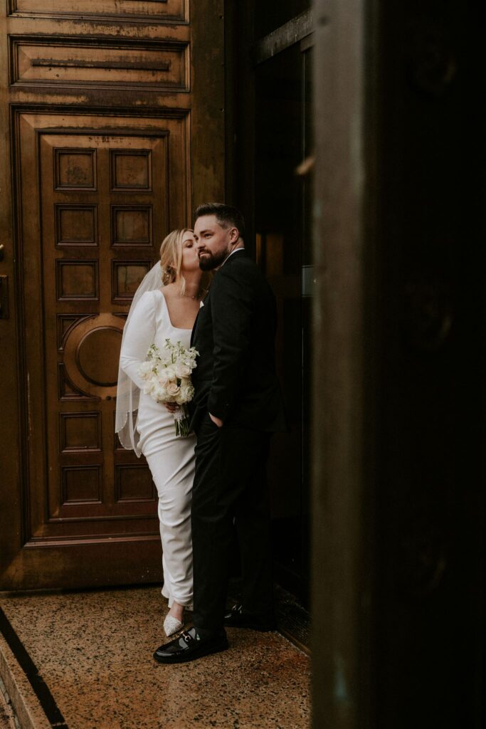 bride and groom almost kissing by a wooden door
